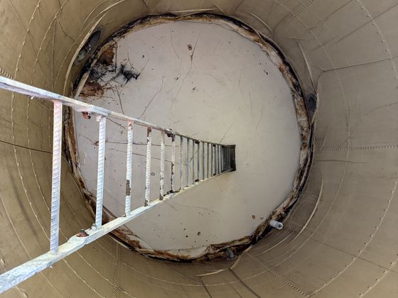 Looking down the internal ladder into a drained steel water tank.