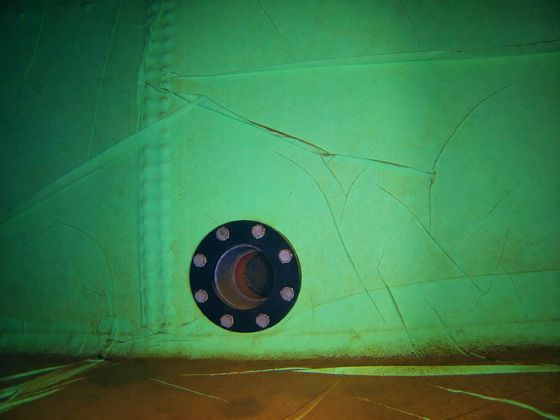 A bolted outlet flange in the lined wall of a water tank, photographed underwater by the ROV.