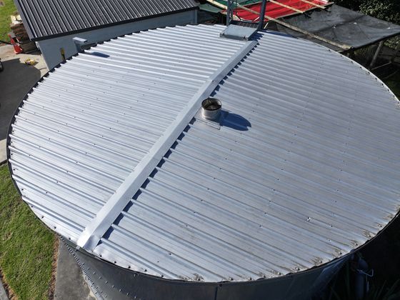 Drone view straight down onto the corrugated roof of a round steel tank.